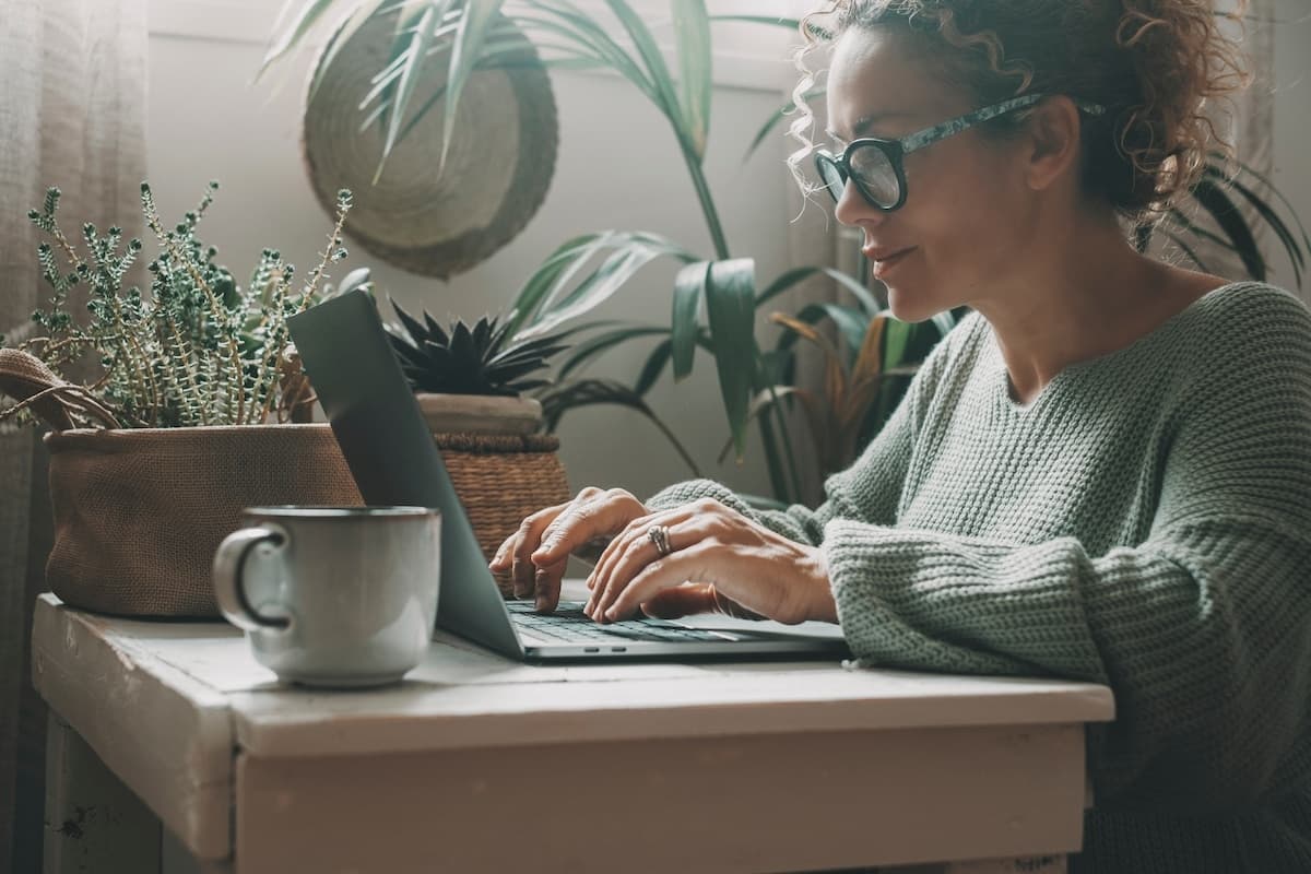 One,Adult,Woman,Writing,On,Laptop,At,Home,In,Green